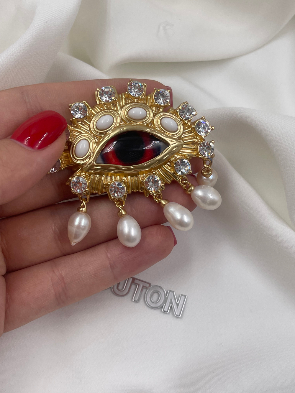 Брошь Скиапар. золотистая в форме красного глаза с жемчугом и стразами