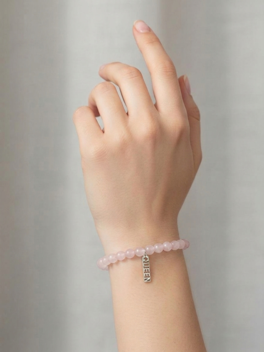 Фото браслета из натурального камня розовый кварц с серебряной подвеской QUEEN на руке