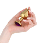 Золотистая анальная пробка с фиолетовым кристаллом - 8,5 см. (Цвет: фиолетовый)