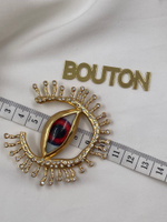 Брошь Скиап. золотистая в форме глаза с подковой из ресниц со стразами красный