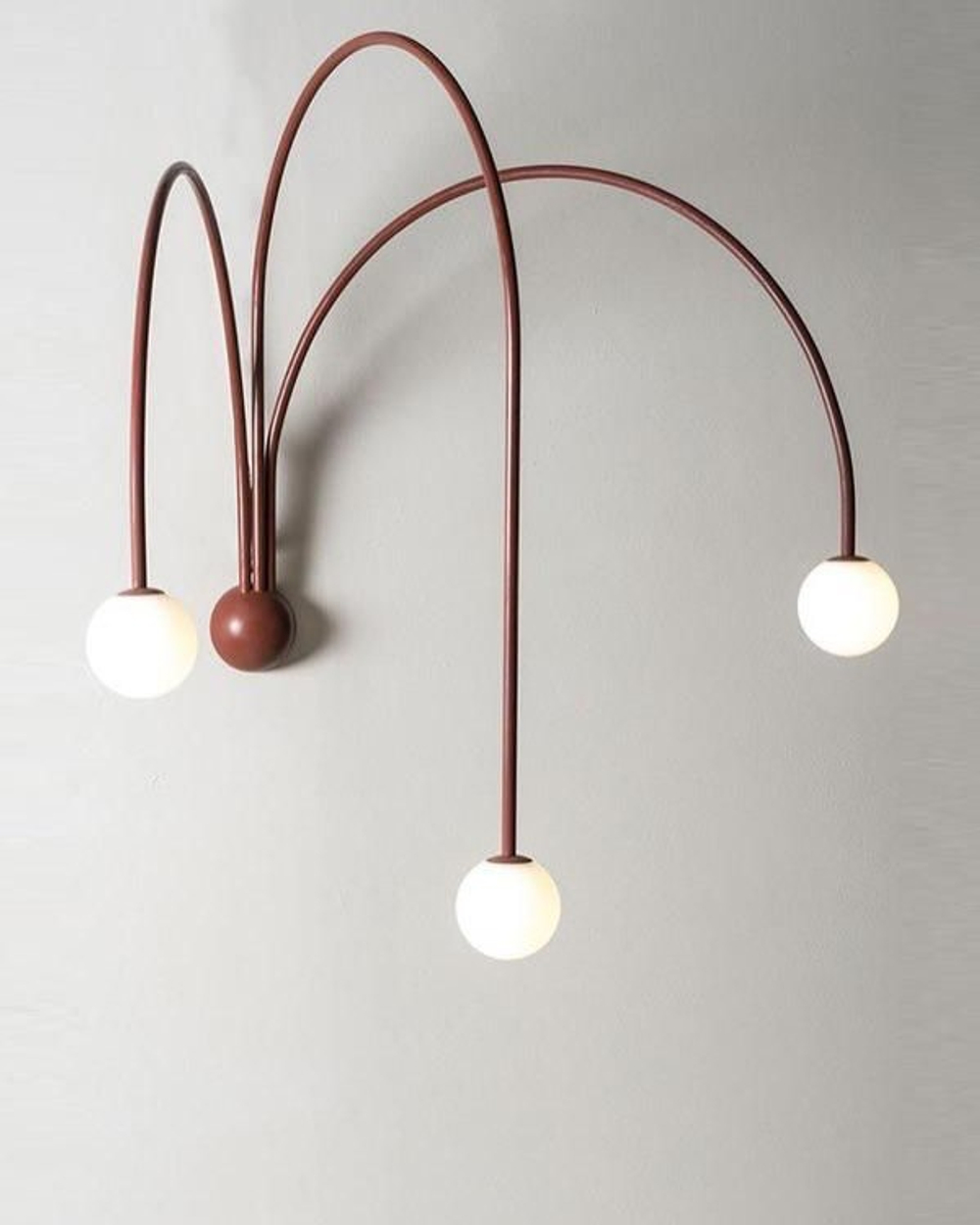 Стильное настенное бра с изящными дугообразными держателями и матовыми шарообразными плафонами.