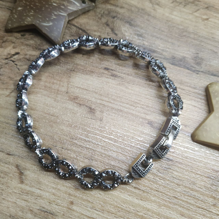 Браслет Vogue Восьмерка круглая стразы графитовые металл серебристый на красном бархате