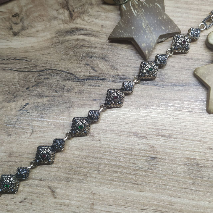 Браслет Vogue 2 ромба стразы графитовые зеленые красные металл золотистый на красном бархате