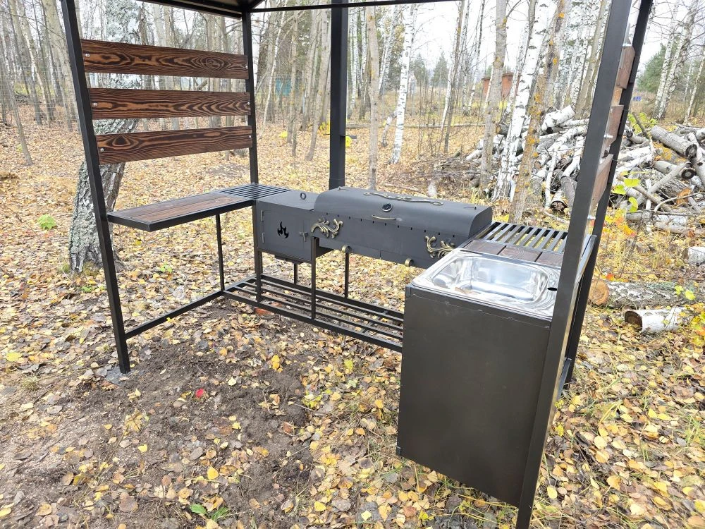 Мангальная зона из стали 5 мм с мойкой (Казань) Если вы хотите купить мангальную зону с мойкой в Казани, присмотритесь к нашему варианту: это мангальная зона 5 мм с крышей (полноценная уличная кухня/зона барбекю), где есть мангал 5 мм с жаровней 90×40×15 (рассчитан примерно на 11 шампуров), крышка барбекю с термодатчиком и шиберами для удобной регулировки тяги и температуры. Также зону можно использовать как коптильню — коптить рыбу, мясо и курицу.  Отдельно предусмотрена печь под казан 5 мм размером 40×40×30 с кольцами под казаны 3/4/6/8/10/12 литров, есть труба 80×80 с заслонкой, колосник и зольник. Для удобства сделаны столик для нарезки (стол металл+дерево), нержавеющая мойка 48×48, дровница и тубус для шампуров. Конструкция разборная, собирается на болтовых соединениях. Зона может быть в наличии в Казани, доступна доставка и установка, а также изготовление мангальной зоны под заказ под ваши размеры.