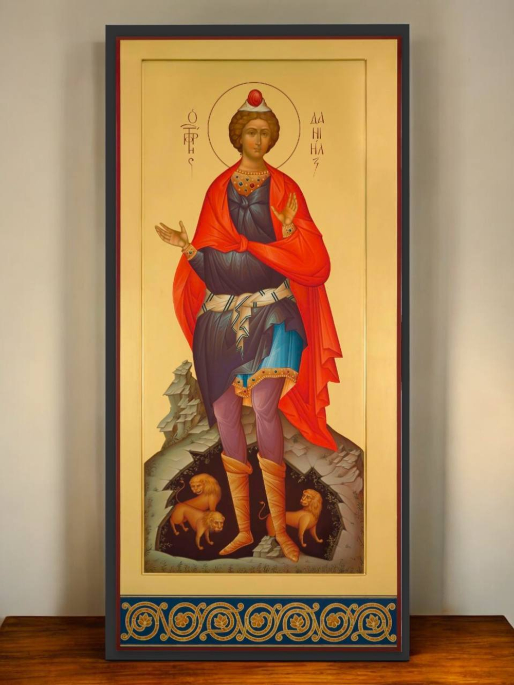 О святом пророке Данииле: Пророк Даниил — один из величайших ветхозаветных праведников, живший в VI веке до н. э. Он был уведён в Вавилон в юности, где прославился своей мудростью, верностью Богу и способностью толковать сны. Благодаря этим дарам он занял высокое положение при дворе царя Навуходоносора.  Самая известная история о Данииле — его чудесное спасение в львином рве. За отказ поклониться языческому идолу, он был брошен ко львам, но остался невредим, ибо Господь закрыл пасти зверям. Это стало символом силы веры, мужества и Божественного покровительства.  Подходит как: — Подарок на именины, день ангела, крещение — Домашняя святыня — Икона для молитвенного уголка  Укрепите свой дом духовной защитой с образом святого пророка Даниила!
