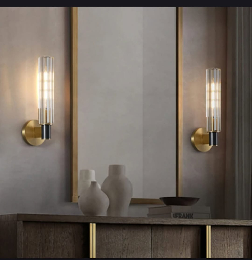 Элегантное настенное бра с вытянутым хрустальным плафоном и металлическим корпусом в тёплом золотом оттенке.