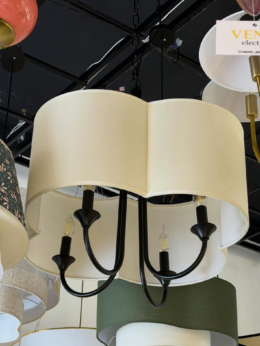 Элегантная люстра с текстильным абажуром в светлом оттенке и черным металлическим основанием.