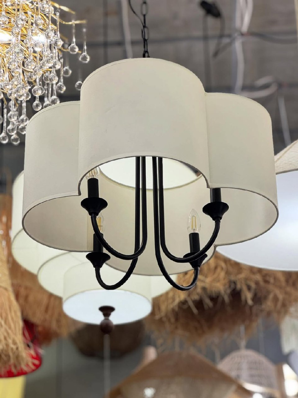 Элегантная люстра с текстильным абажуром в светлом оттенке и черным металлическим основанием.