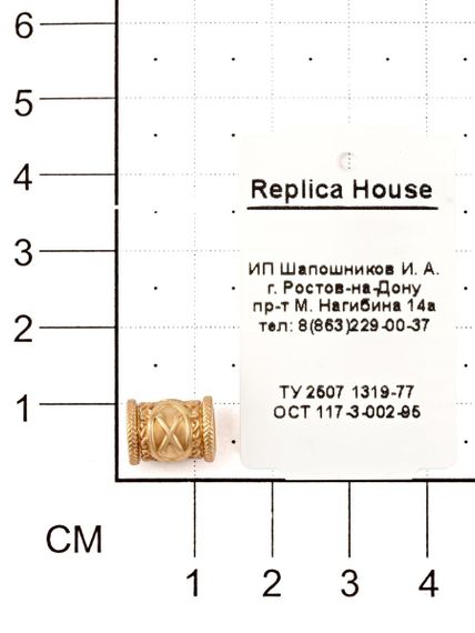 Фотография шарма Гебо из красного золота 585 пробы на размерной сетке.